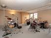 ein großer heller Unterrichtsraum mit drei Mapex drum Sets und professionellem Audio Equipment
